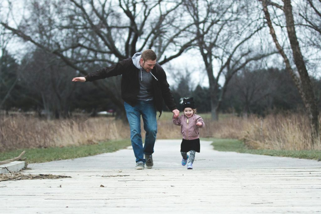 Dad and daughter enjoying a walk in the park, symbolizing love and togetherness.